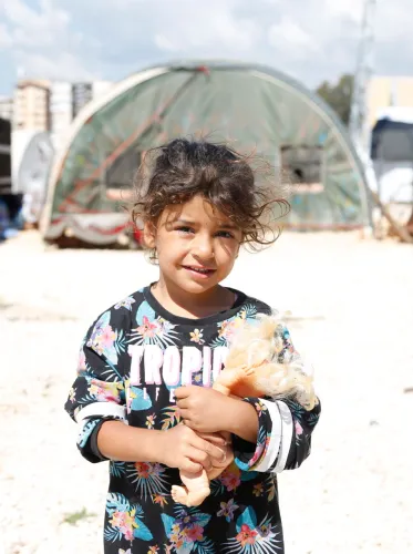 Een meisje houdt haar knuffel vast in een tijdelijk opvangkamp in Hatay, Turkije, op 1 mei 2023, 3 maanden nadat het zuidoosten van Turkije en het noordwesten van Syrië warden getroffen door een reeks verwoestende aardbevingen. © UNICEF/UN0835808/Kiliç
